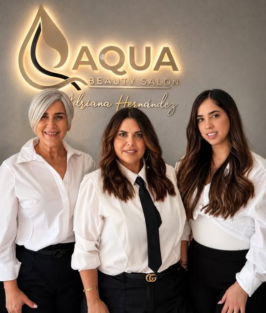 Parte del equipo de Aqua Beauty Salón bajo el letrero